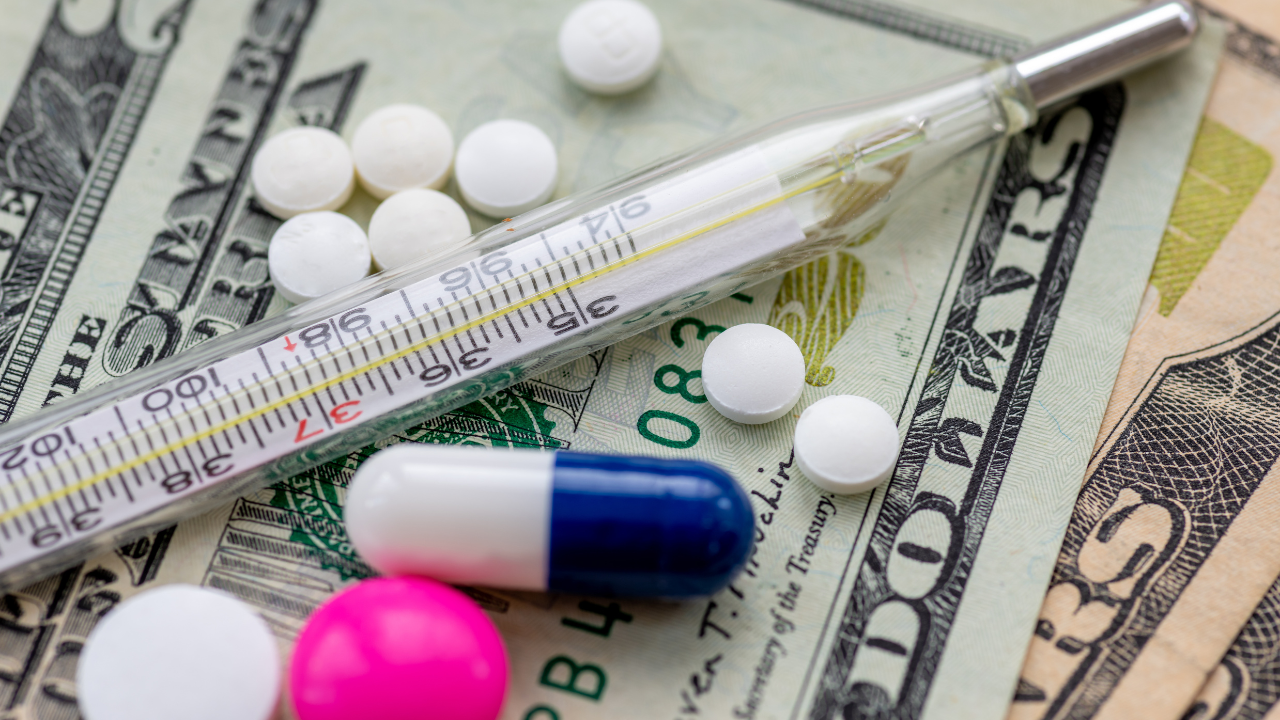 Close up of medicine and a thermometer on top of Dollar bills. Heath care cost, big pharma concept. Image Credit: Adobe Stock Images/Ming
