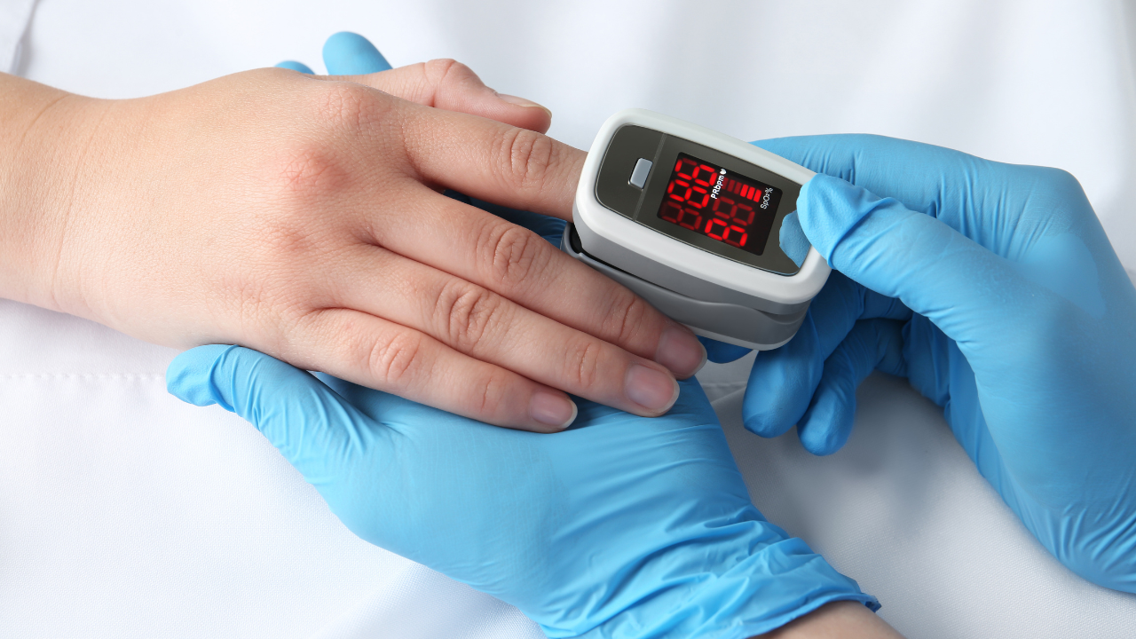 Doctor examining patient with modern fingertip pulse oximeter in bed, closeup. Image Credit: Adobe Stock Images/New Africa