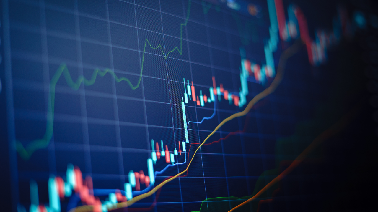 Closeup financial chart with uptrend line candlestick graph in stock market on blue color monitor background. Image Credit: Adobe Stock Images/iamchamp