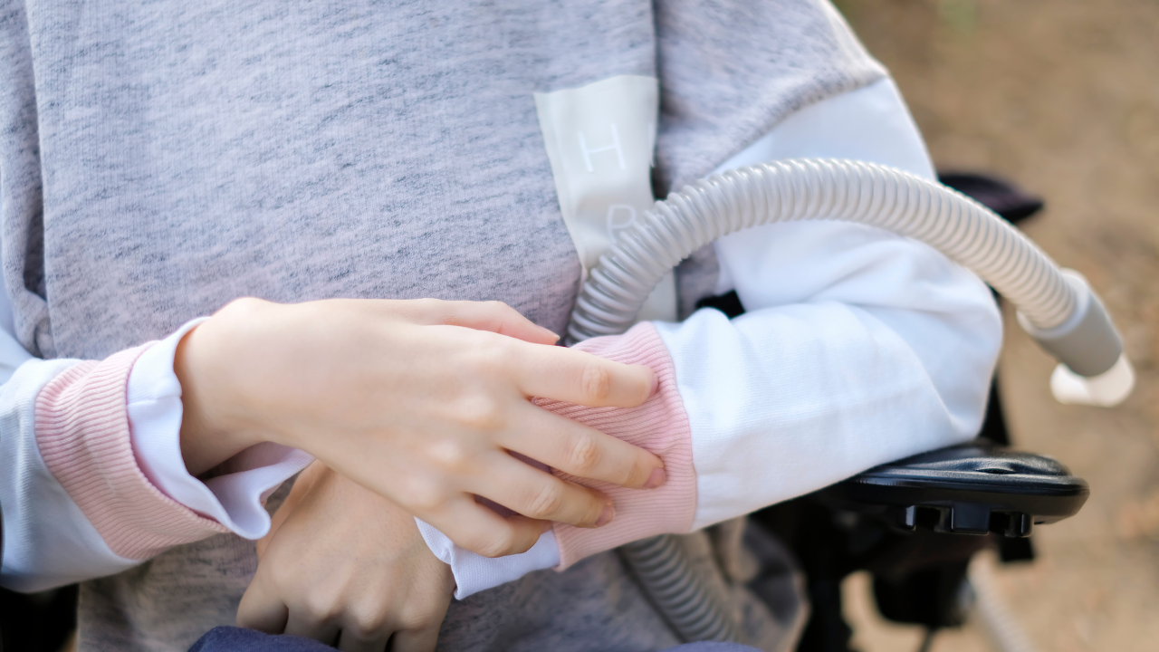 Hands of a disabled person with muscular dystrophy holding a ventilator for deep breathing, concept, background. Image Credit: Adobe Stock Images/ins 