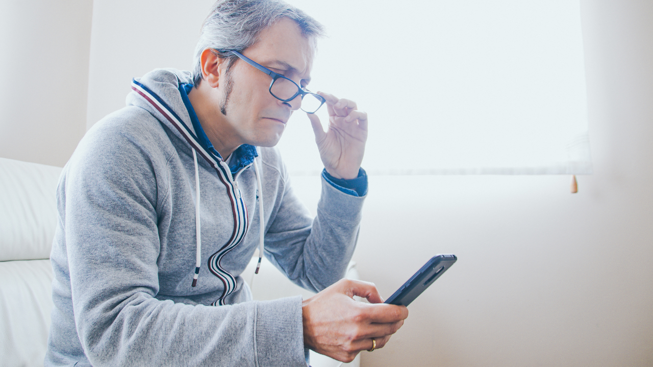 40's man with glasses with presbyopia looking at the phone. Image Credit: Adobe Stock Images/Marcos Ferreiro