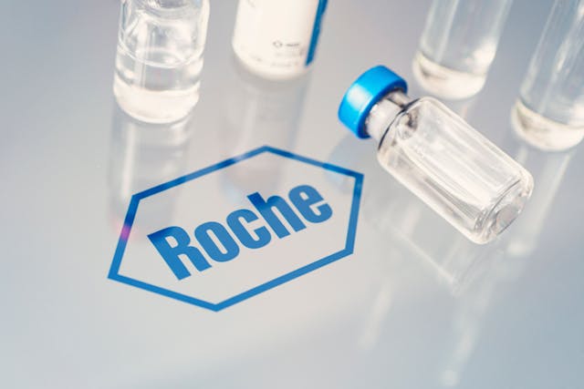Image credit: diy13 | stock.adobe.com. Vials of liquid on a white table and the logo of a large pharmaceutical company Roche.