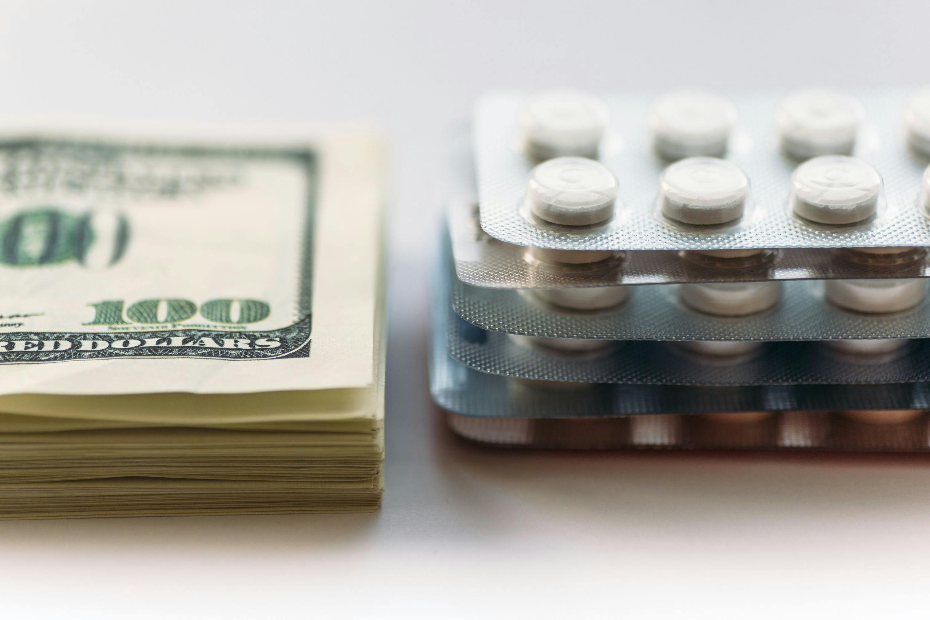 Bundle of money and pack of medication tablets or drug pills, close-up. Expensive health care concept