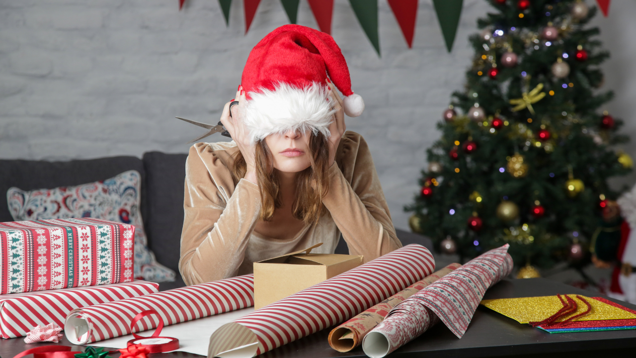 Depressed frustrated woman wrapping Christmas gift boxes, winter holiday stress concept. Image Credit: Adobe Stock Images/triocean
